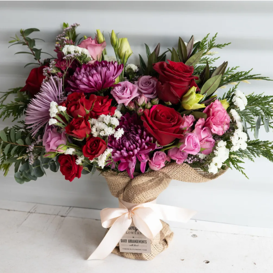 Colorful bouquet of flowers wrapped in burlap and tied together with a pink bow